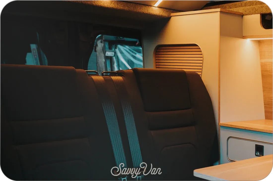 The mirrored screen switched off, reflecting the rear seats and kitchen of a van