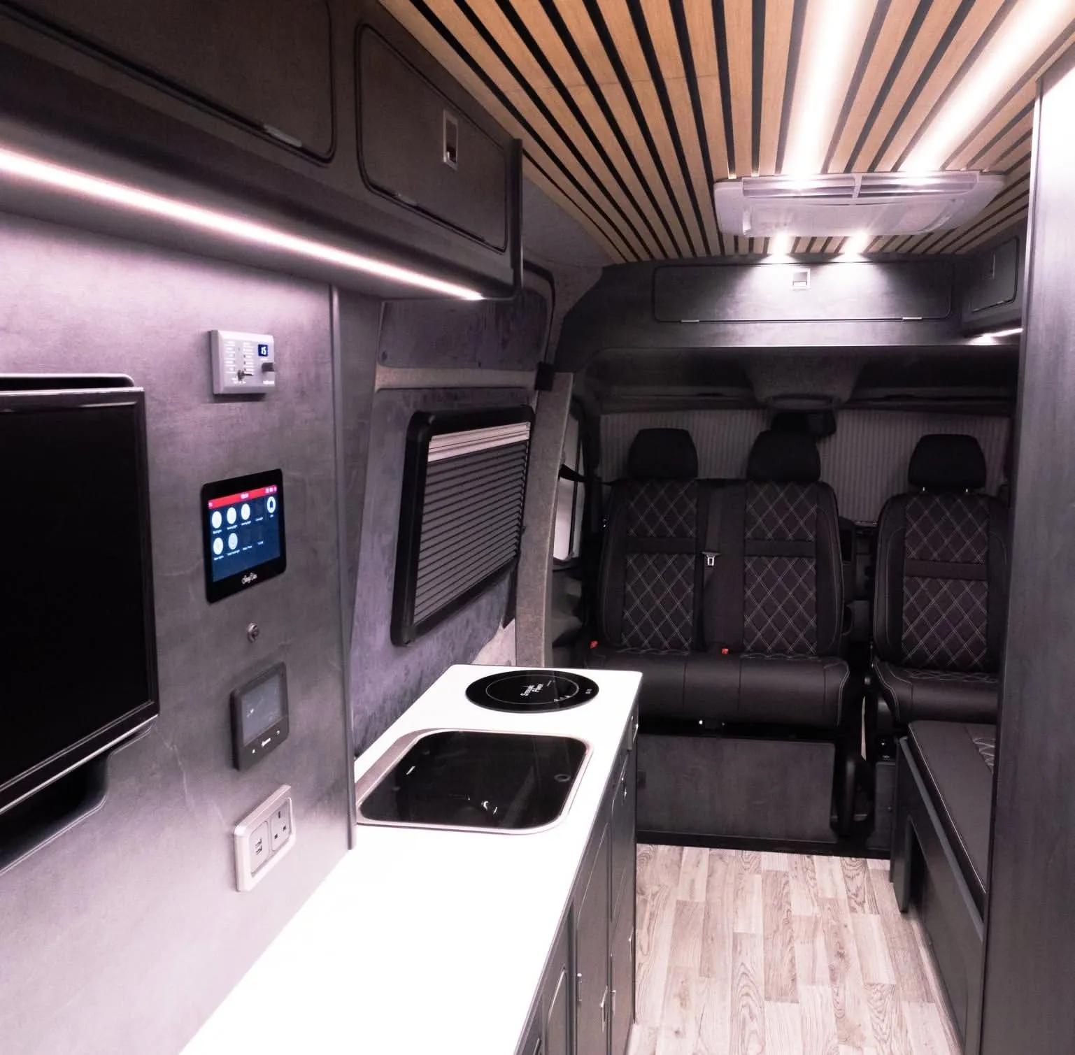 Inside a Custom Built Campervans conversion, with a SavvyVan panel on the wall above the kitchen