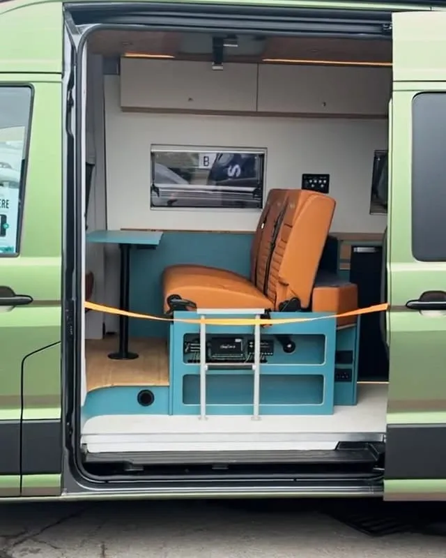 The SavvyVan demonstration van with its side door open, showing a seat and a table inside
