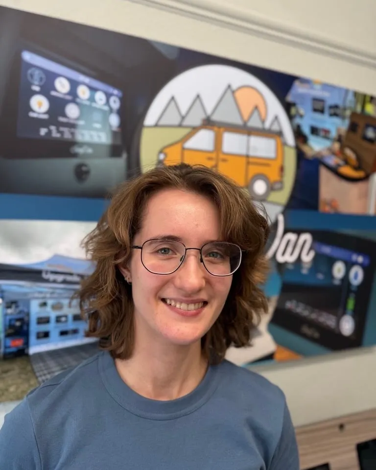 Ana smiling in the SavvyVan office, in front of a SavvyVan display