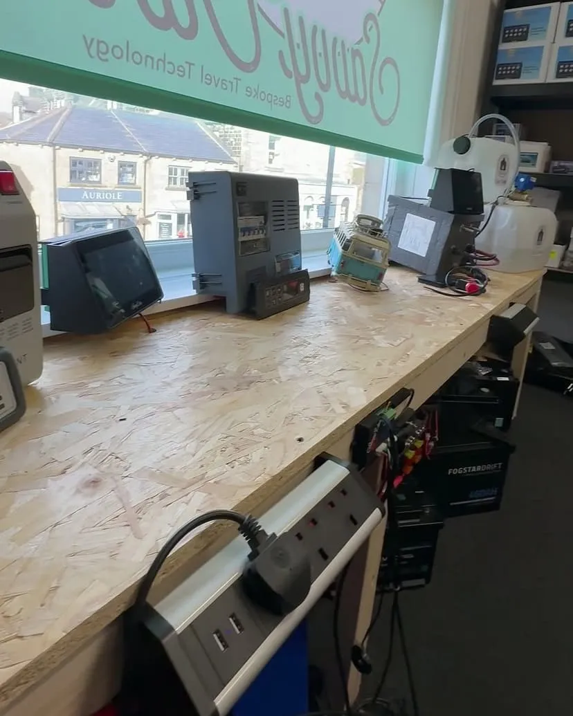 A workbench in the new SavvyVan office, with panels on test and a window blind printed with the SavvyVan logo