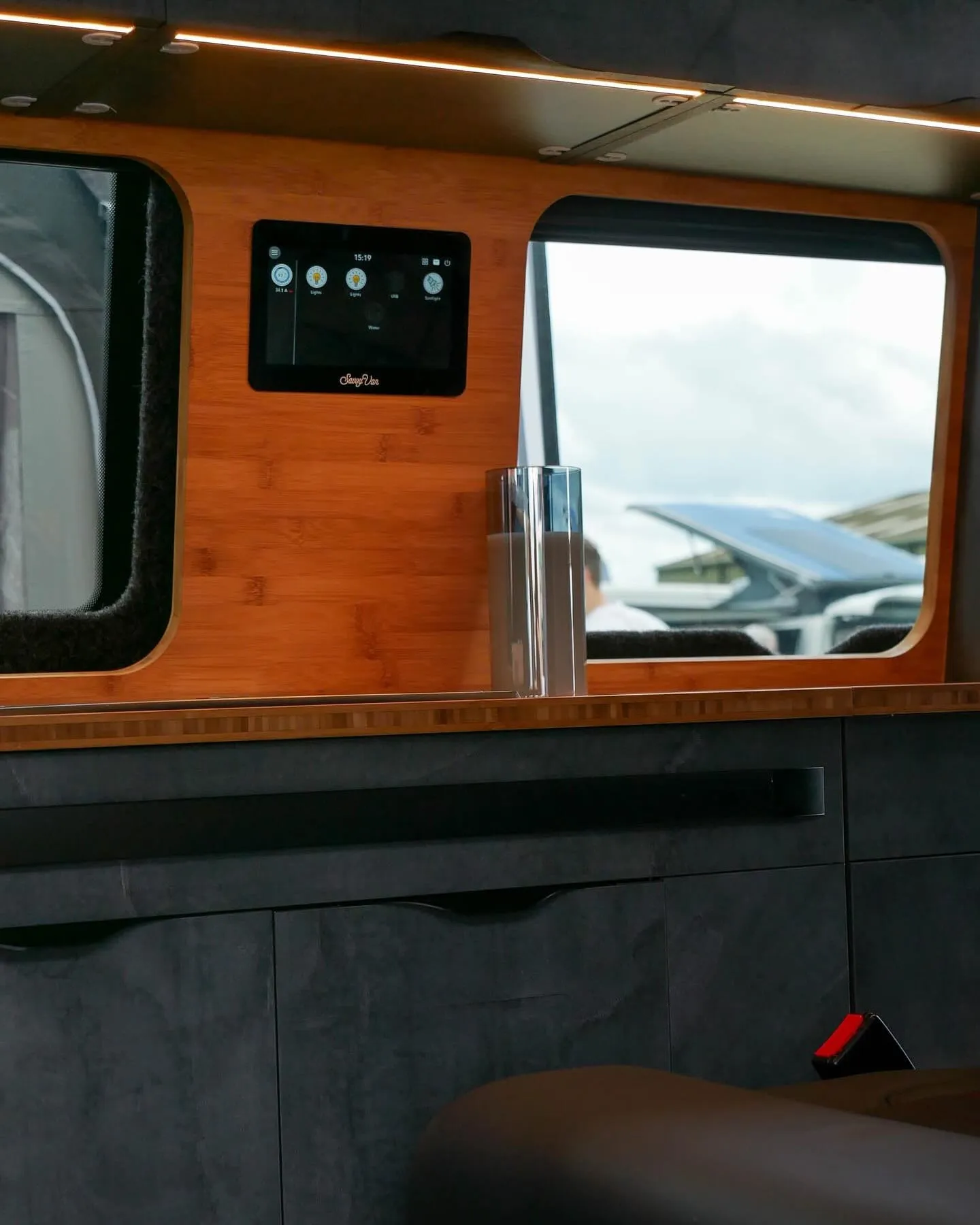 A SavvyVan panel fitted on a wooden wall inside a campervan, beside a window