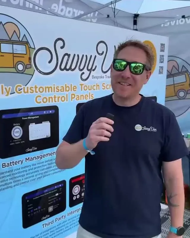 One of the SavvyVan team, in sunglasses, on the stand at Newbury in front of SavvyVan display boards