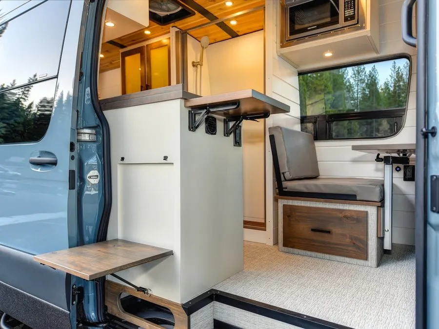 A finished campervan interior seen through the open side door