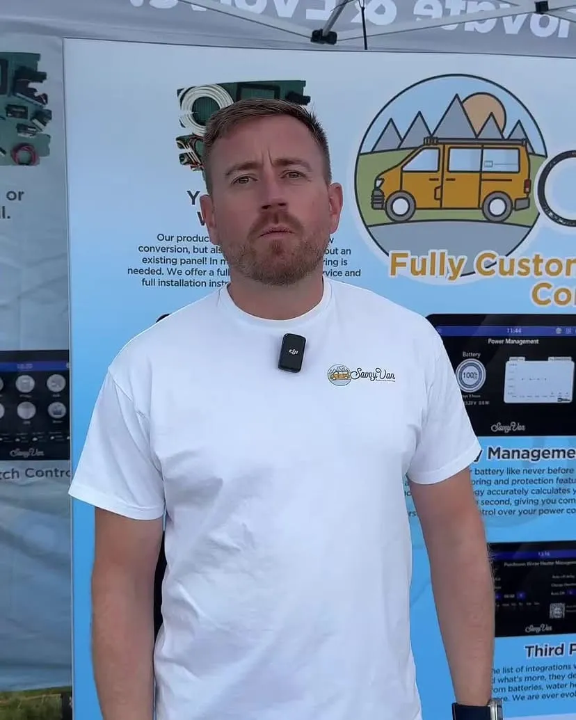 One of the SavvyVan team on the stand at Vanlife Festival, in front of SavvyVan display boards